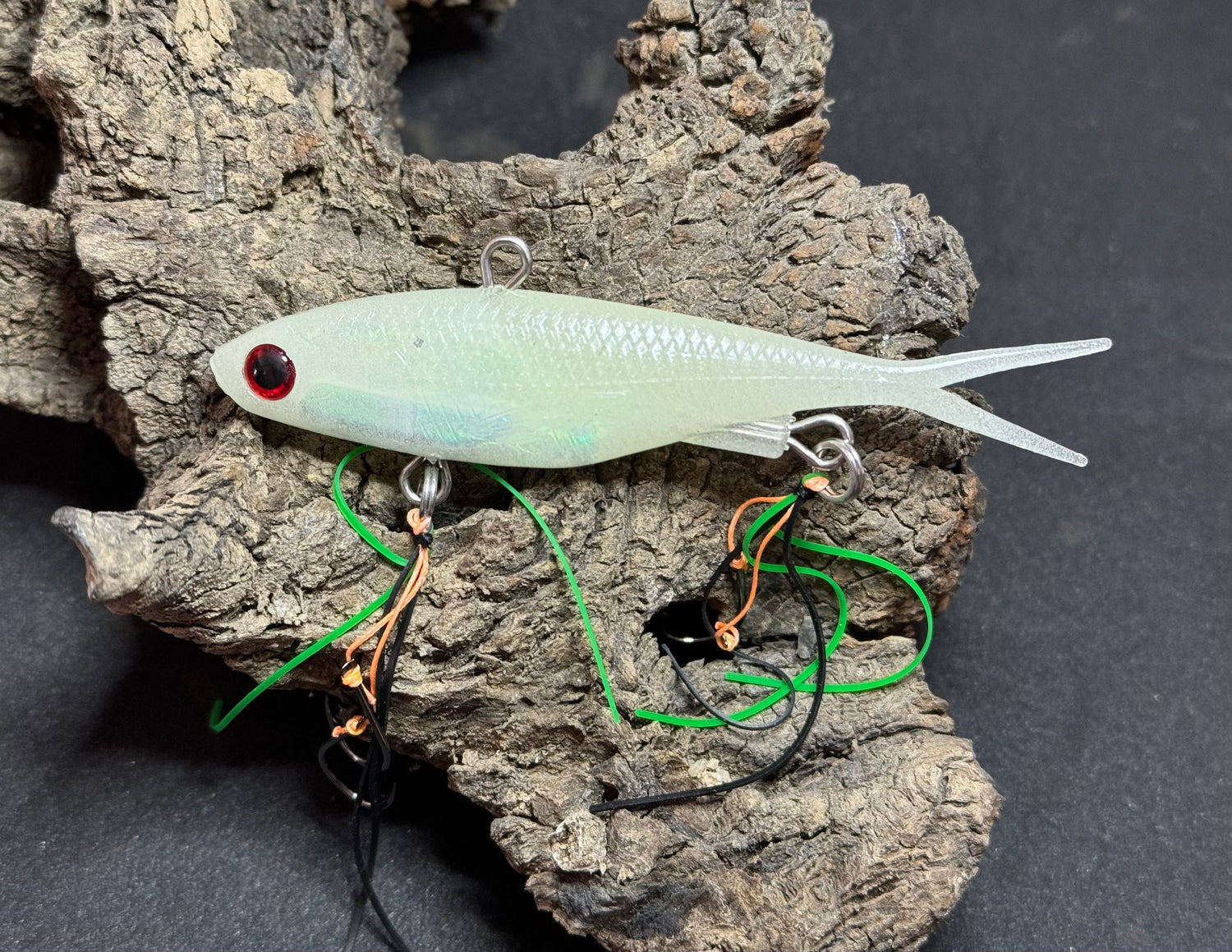 A multicoloured fishing lure with a vibrating tail designed to imitate the movement of fish, equipped with two sets of stinger hooks.