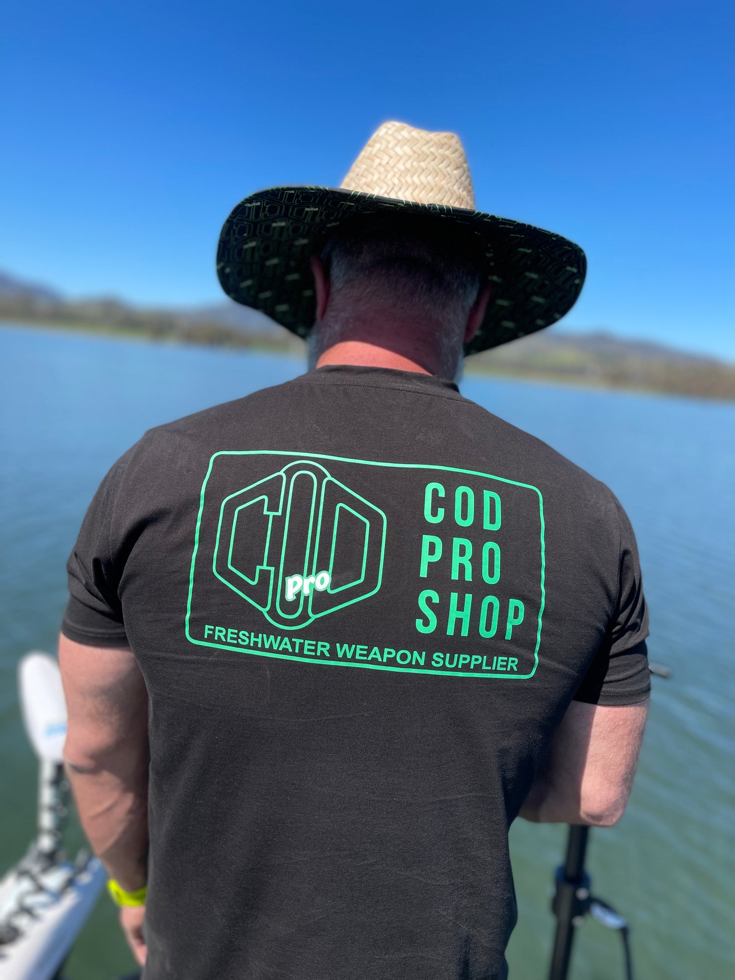 A man wearing a dad body t-shirt black short sleeve t-shirt with a subtle logo on the back