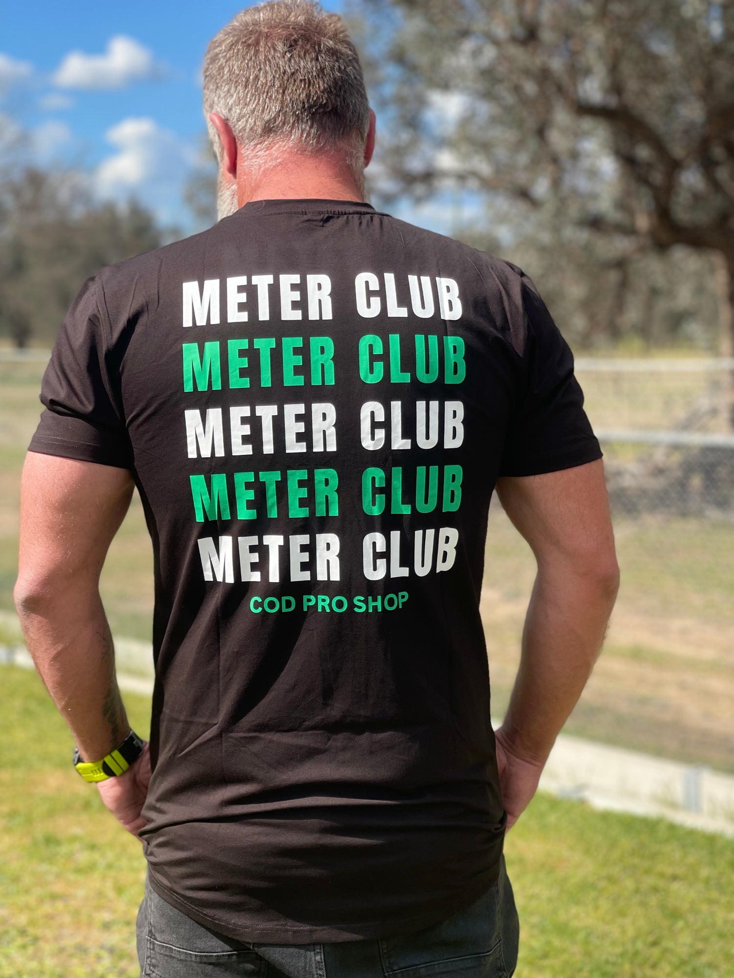 A man wearing a fishing dad body t-shirt black short sleeve t-shirt with a subtle logo on the back