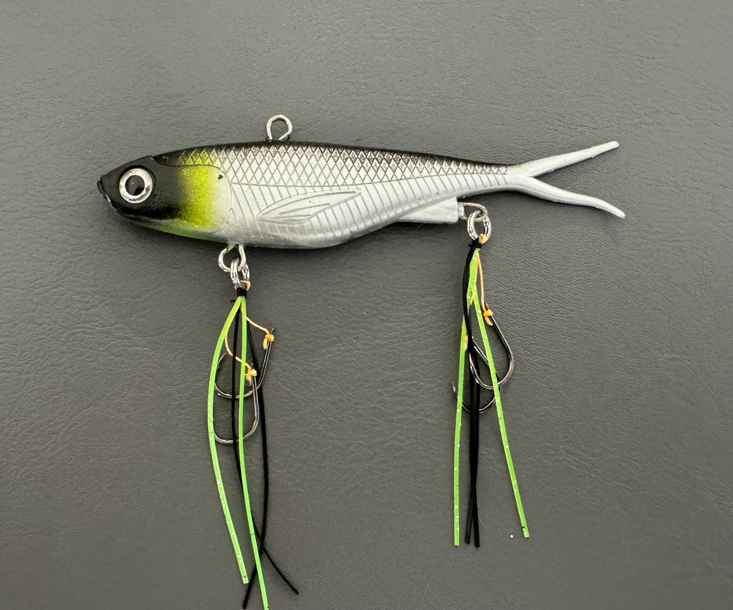 A multicoloured fishing lure with a vibrating tail designed to imitate the movement of fish, equipped with two sets of stinger hooks.