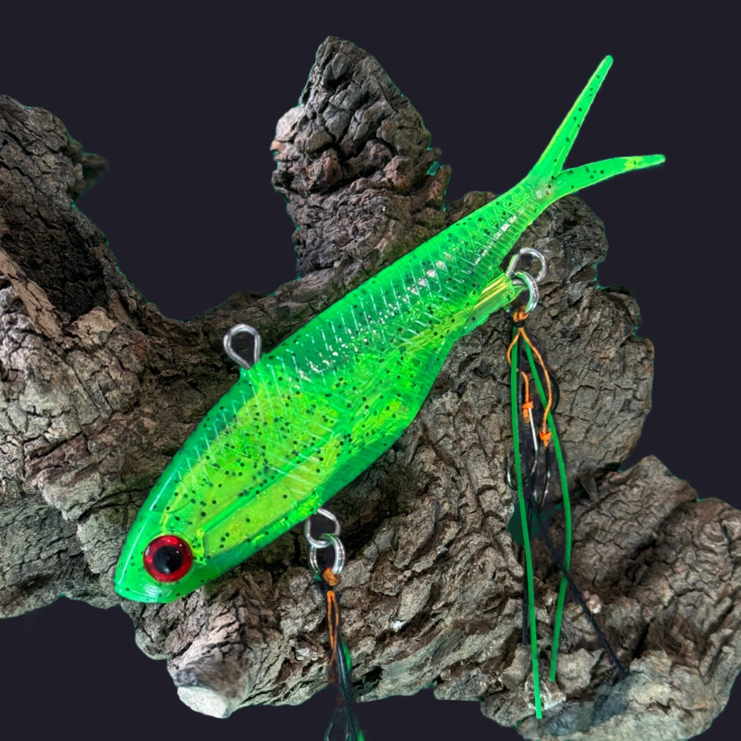 A multicoloured fishing lure with a vibrating tail designed to imitate the movement of fish, equipped with two sets of stinger hooks.