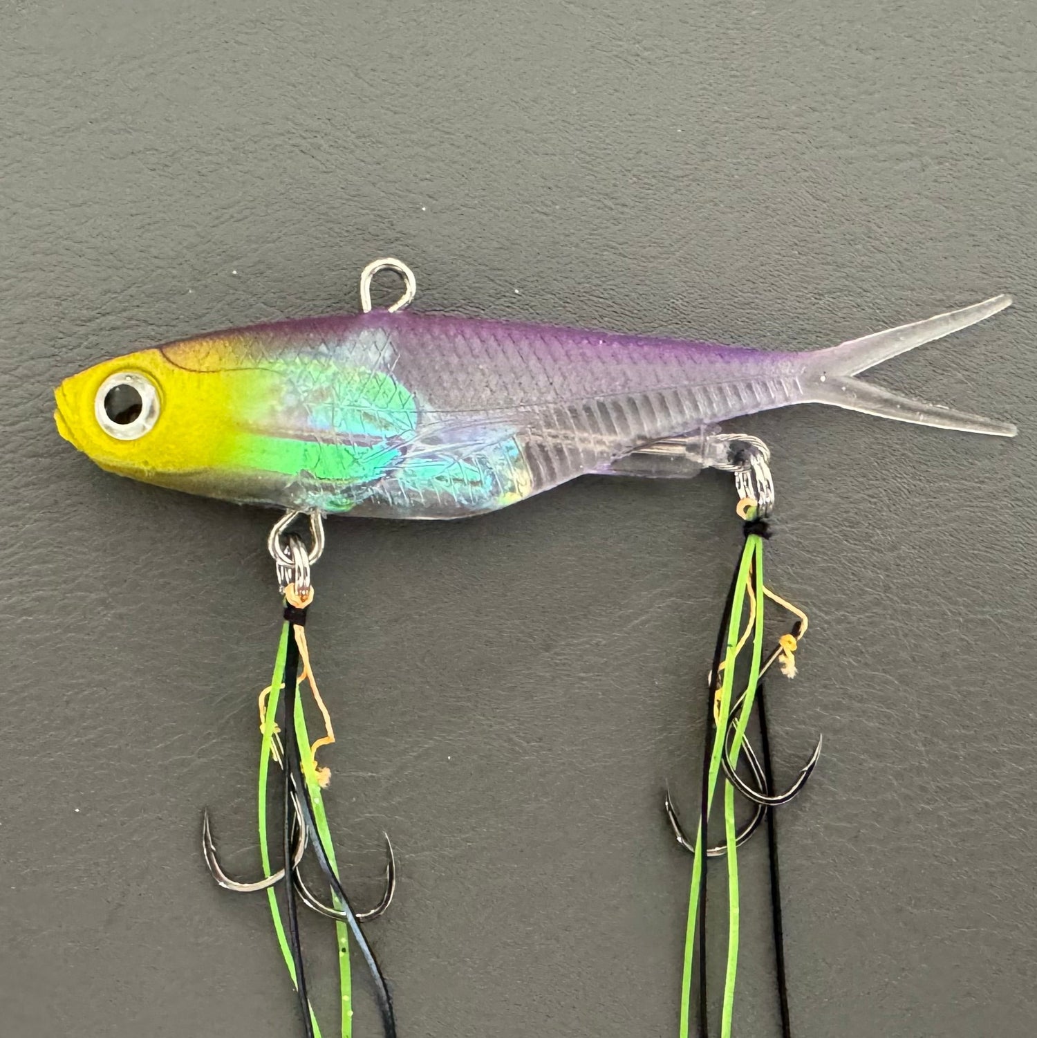 A multicoloured fishing lure with a vibrating tail designed to imitate the movement of fish, equipped with two sets of stinger hooks.