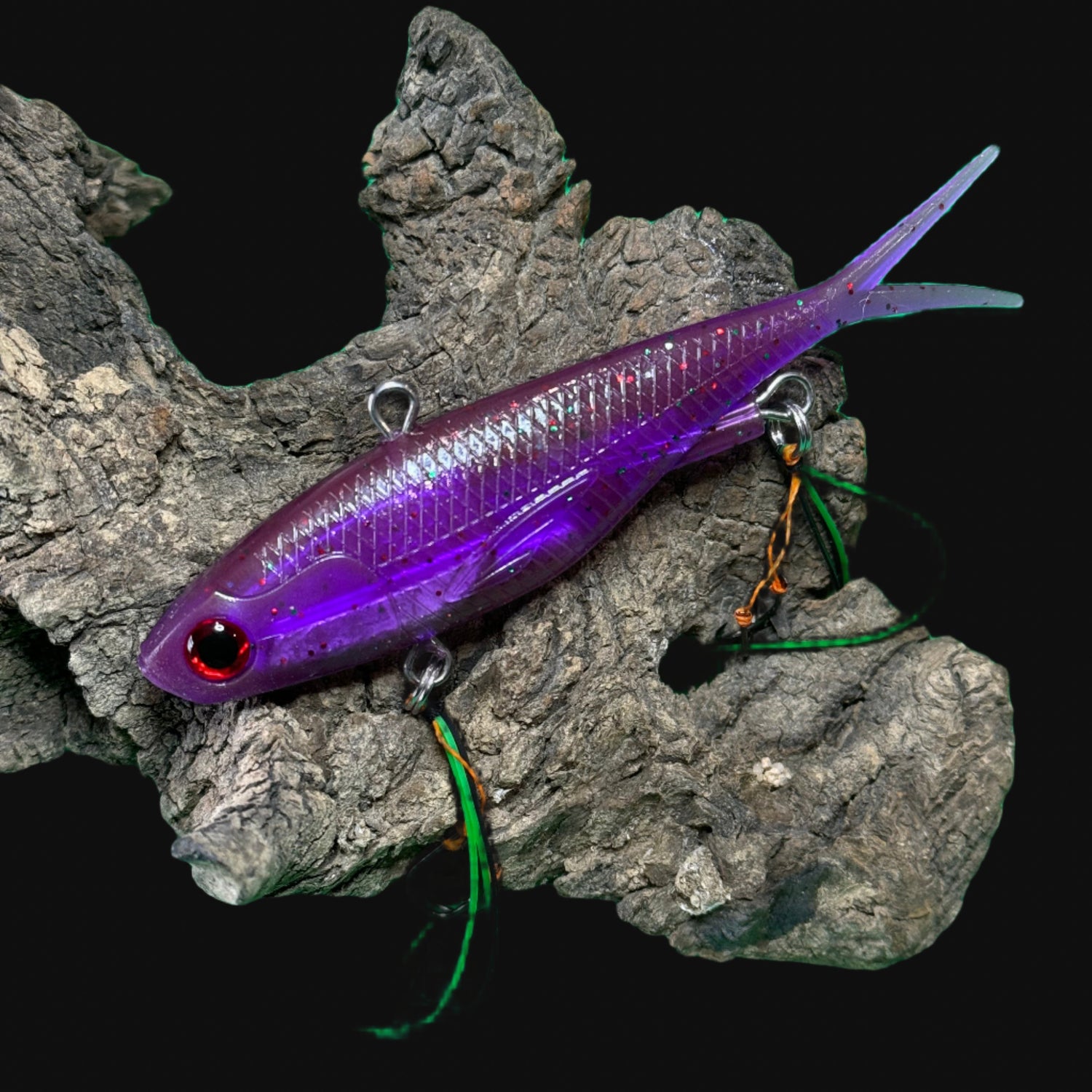 A multicoloured fishing lure with a vibrating tail designed to imitate the movement of fish, equipped with two sets of stinger hooks.