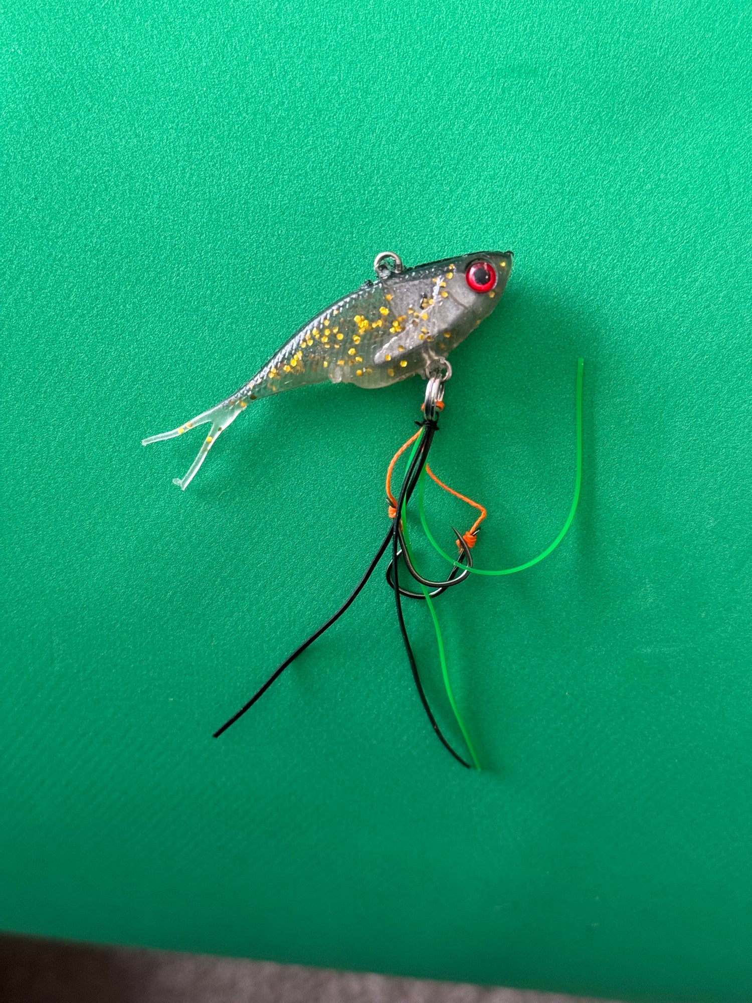 A grey with gold coloured fishing lure named 'Shammy Vibes' soft vibe 55mm yellow belly assist hooks