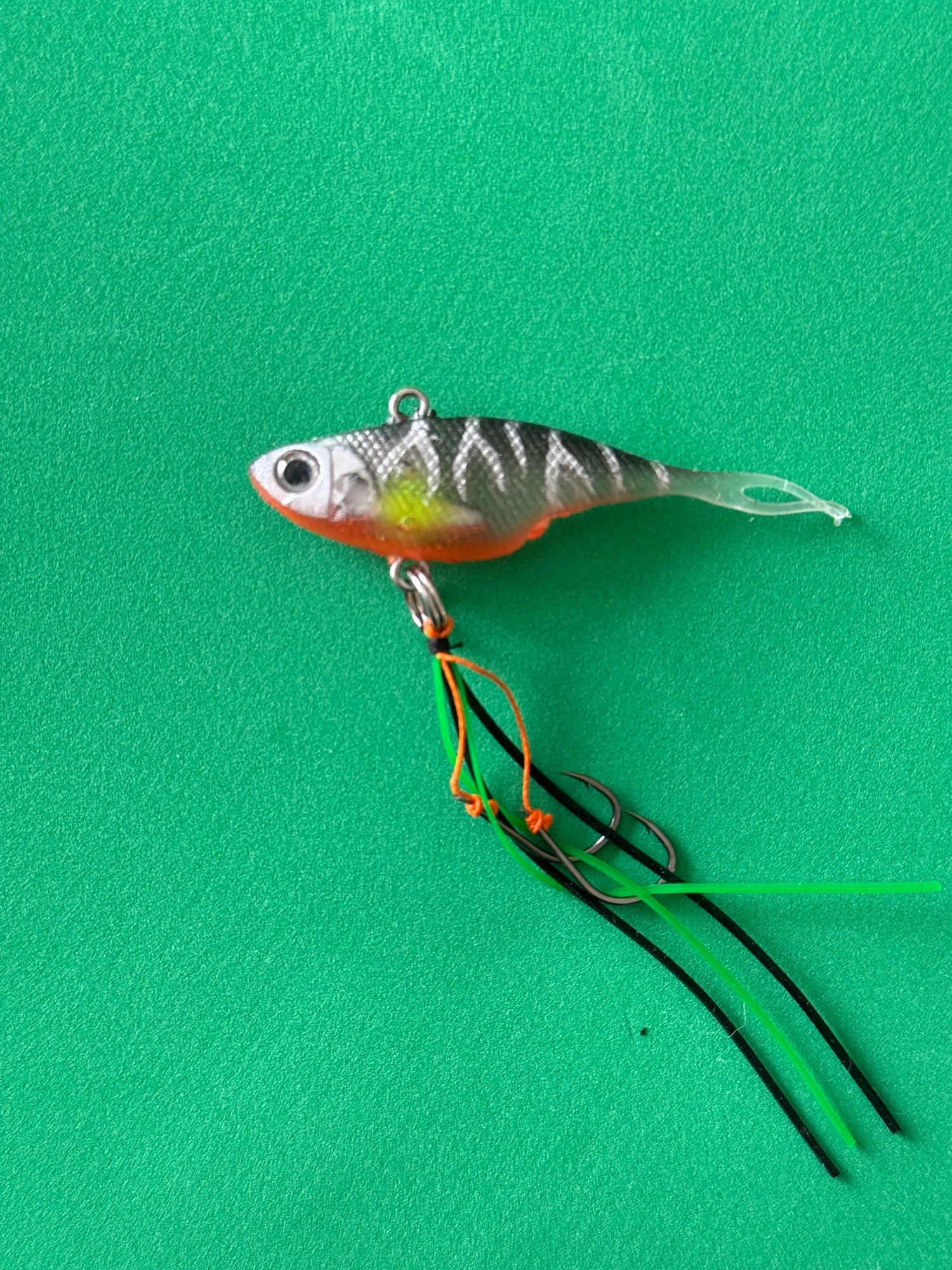 A grey with stripes coloured fishing lure named 'Shammy Vibes' soft vibe 55mm yellow belly assist hooks