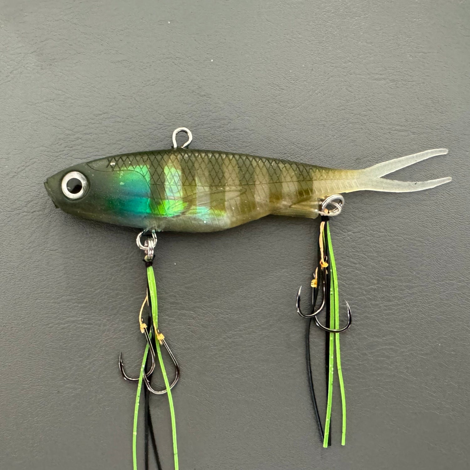 A multicoloured fishing lure with a vibrating tail designed to imitate the movement of fish, equipped with two sets of stinger hooks.