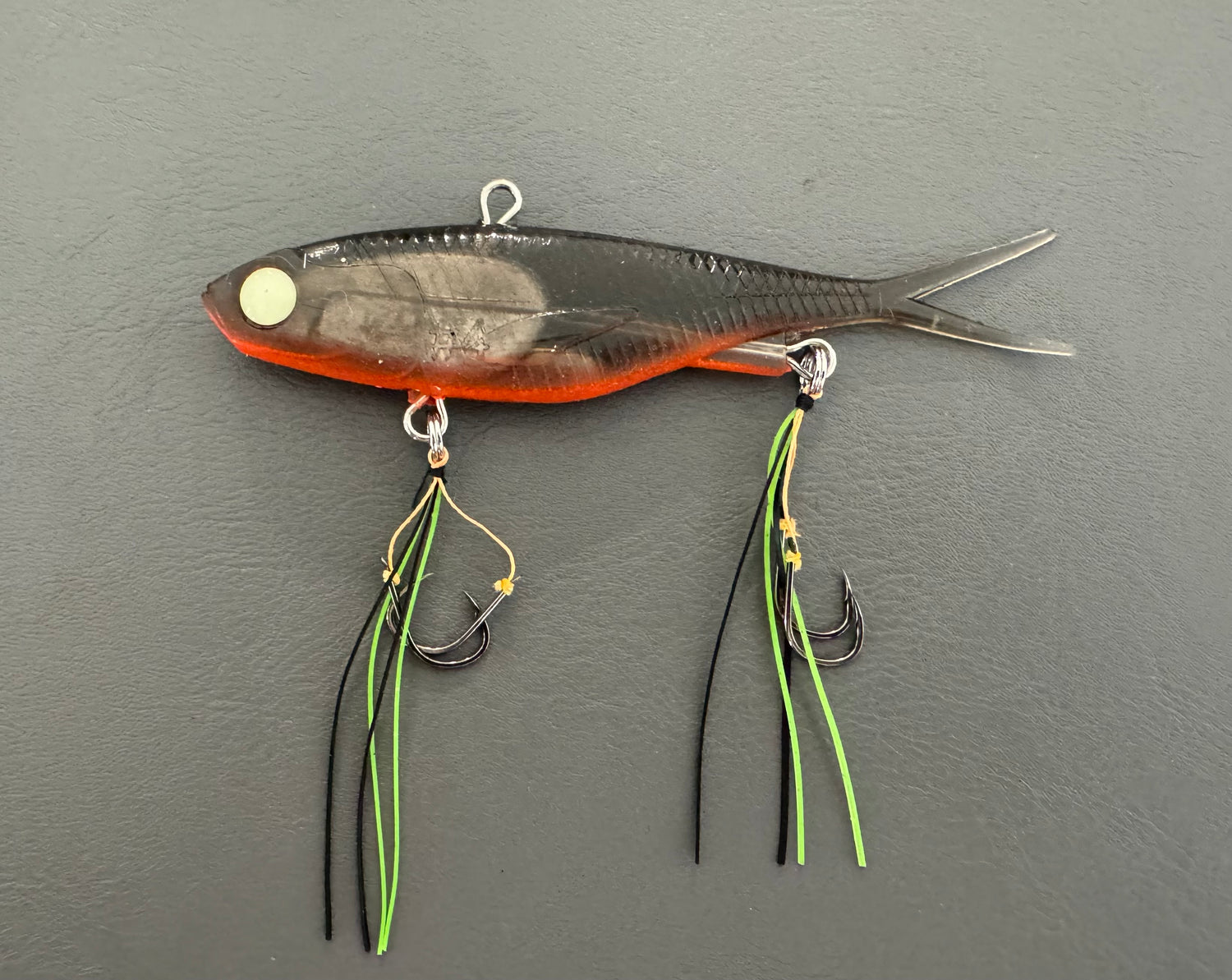 A multicoloured fishing lure with a vibrating tail designed to imitate the movement of fish, equipped with two sets of stinger hooks.