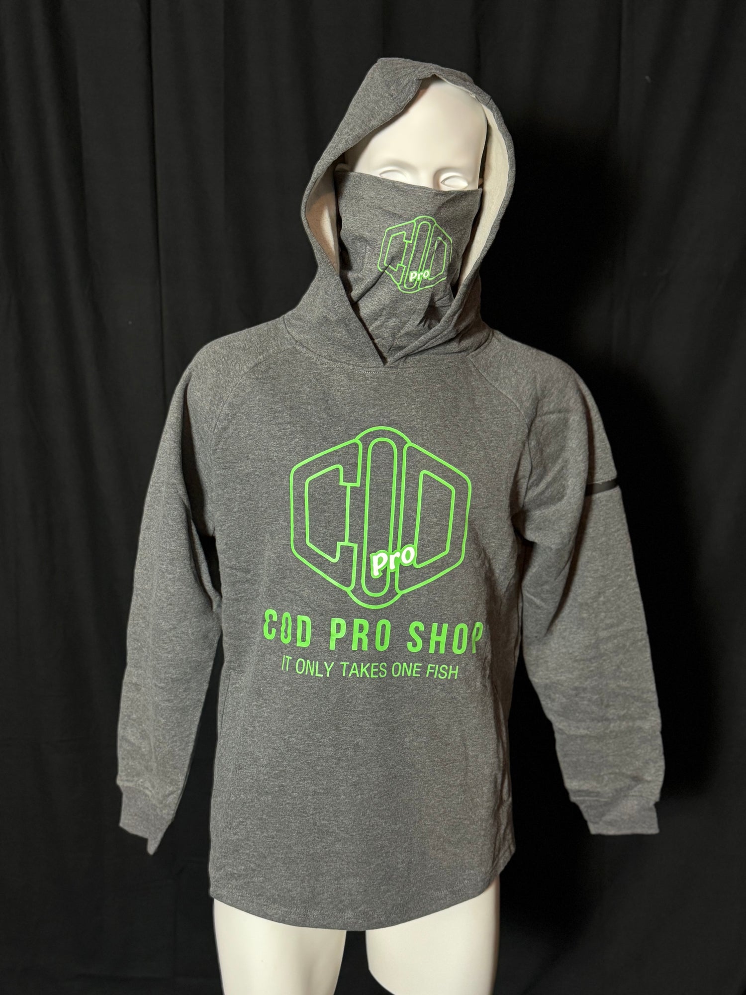A grey hoodie with the text 'COD PRO SHOP' displayed prominently, featuring a hood and a built-in neck scarf. The hoodie is presented on a mannequin against a black background.