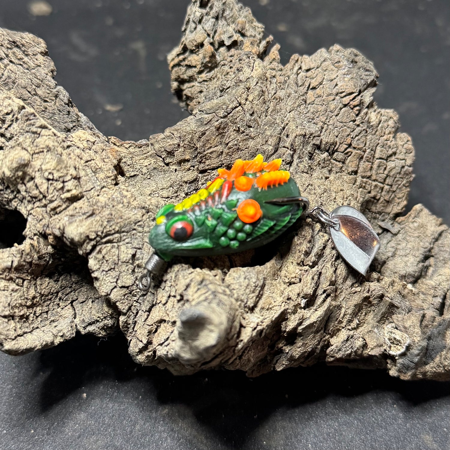 A collection of colorful fishing lures designed to resemble frogs, displayed on a piece of driftwood.