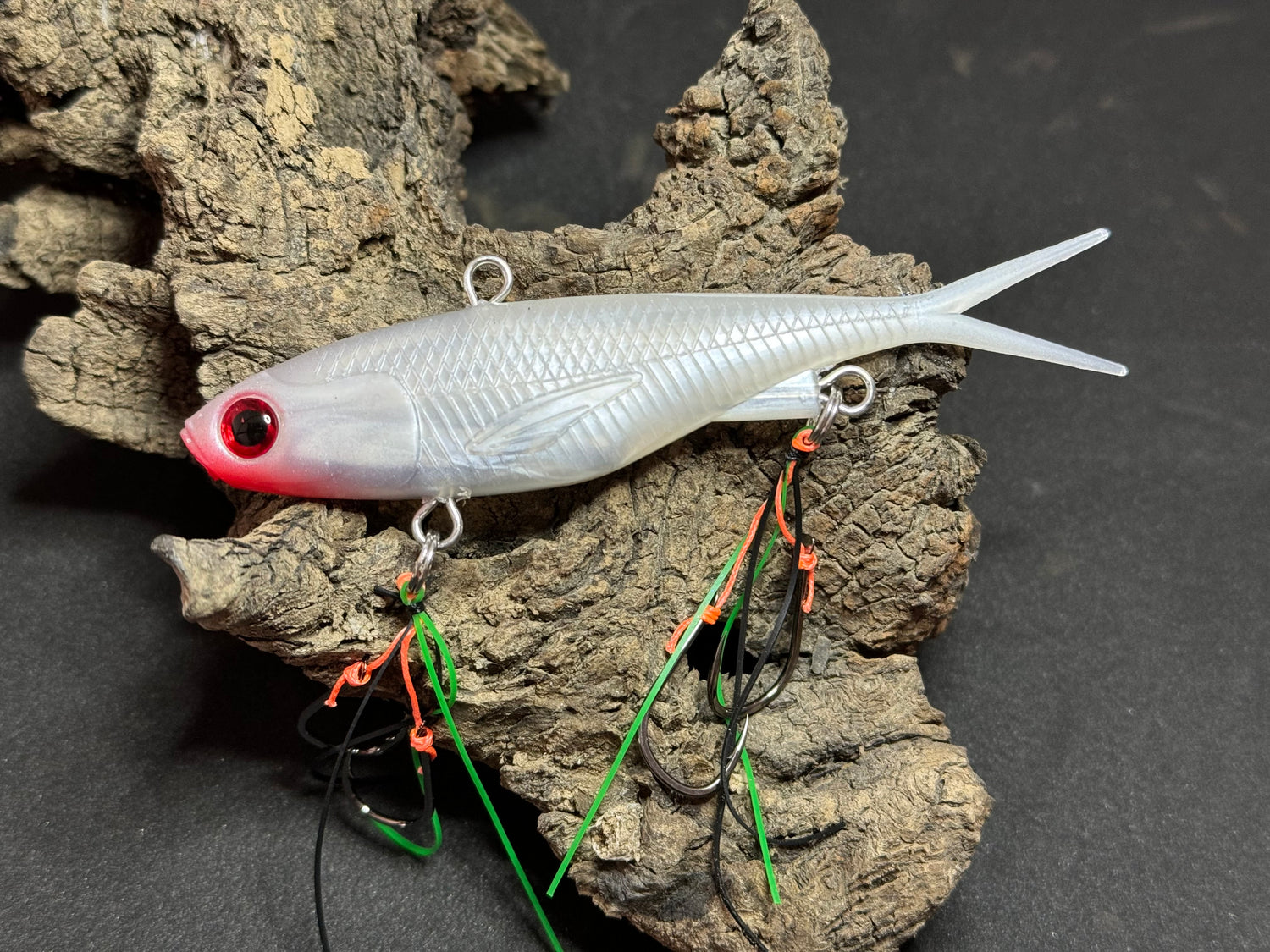A multicoloured fishing lure with a vibrating tail designed to imitate the movement of fish, equipped with two sets of stinger hooks.
