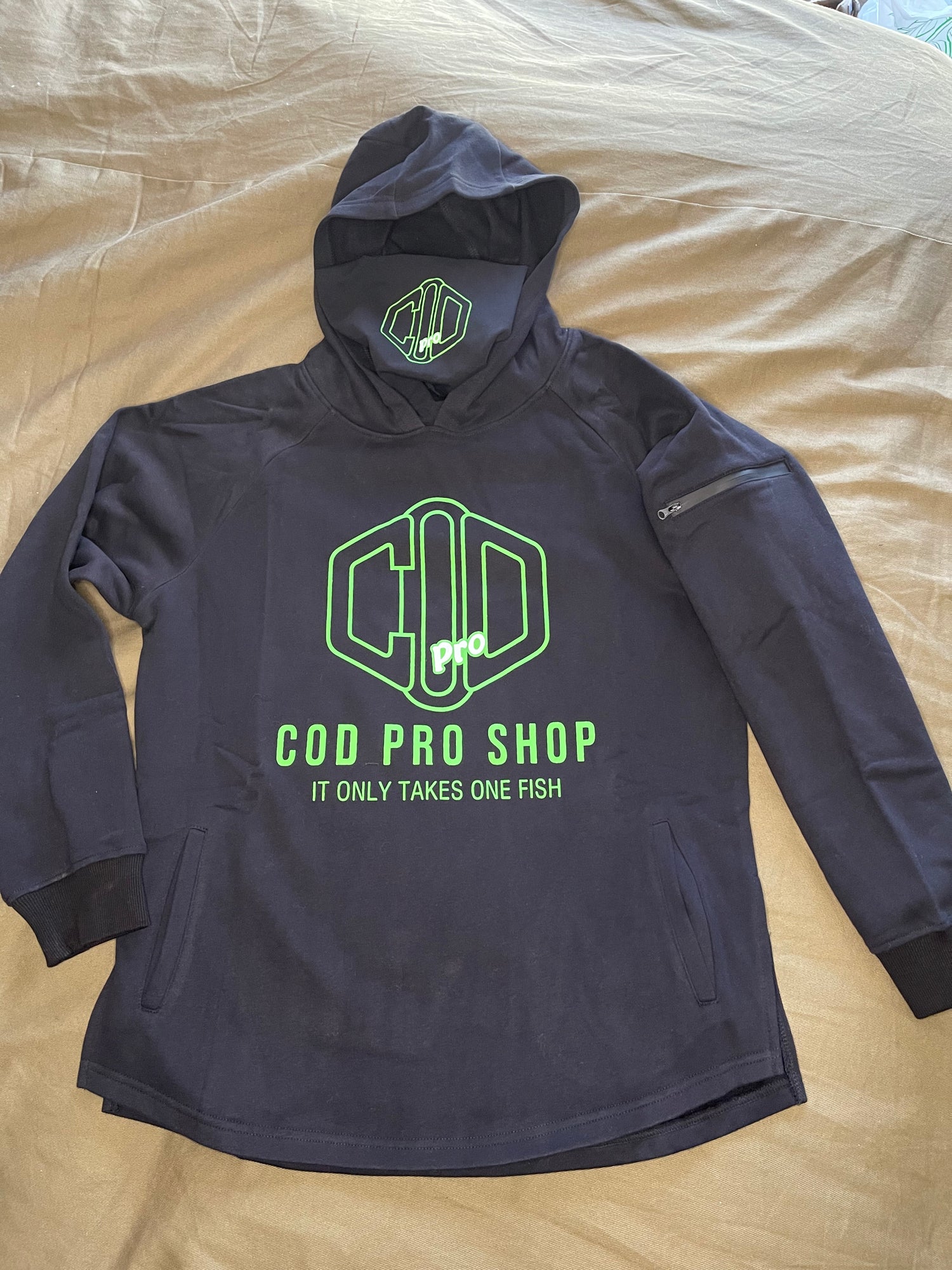 A black hoodie with the text 'COD PRO SHOP' displayed prominently, featuring a hood and a built-in neck scarf. The hoodie is presented on a mannequin against a black background.