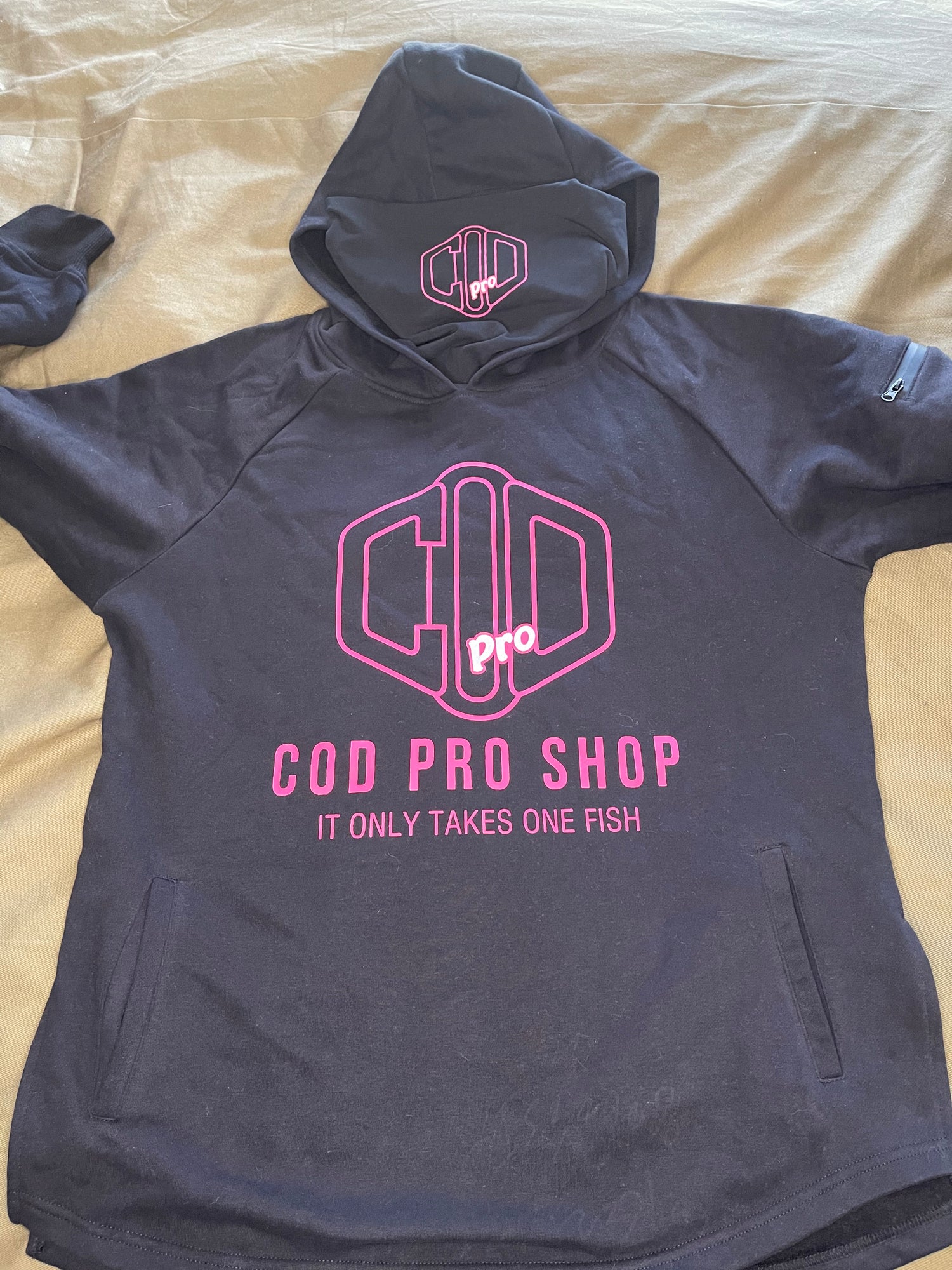 A black hoodie with the text 'COD PRO SHOP' displayed prominently, featuring a hood and a built-in neck scarf. The hoodie is presented on a mannequin against a black background.
