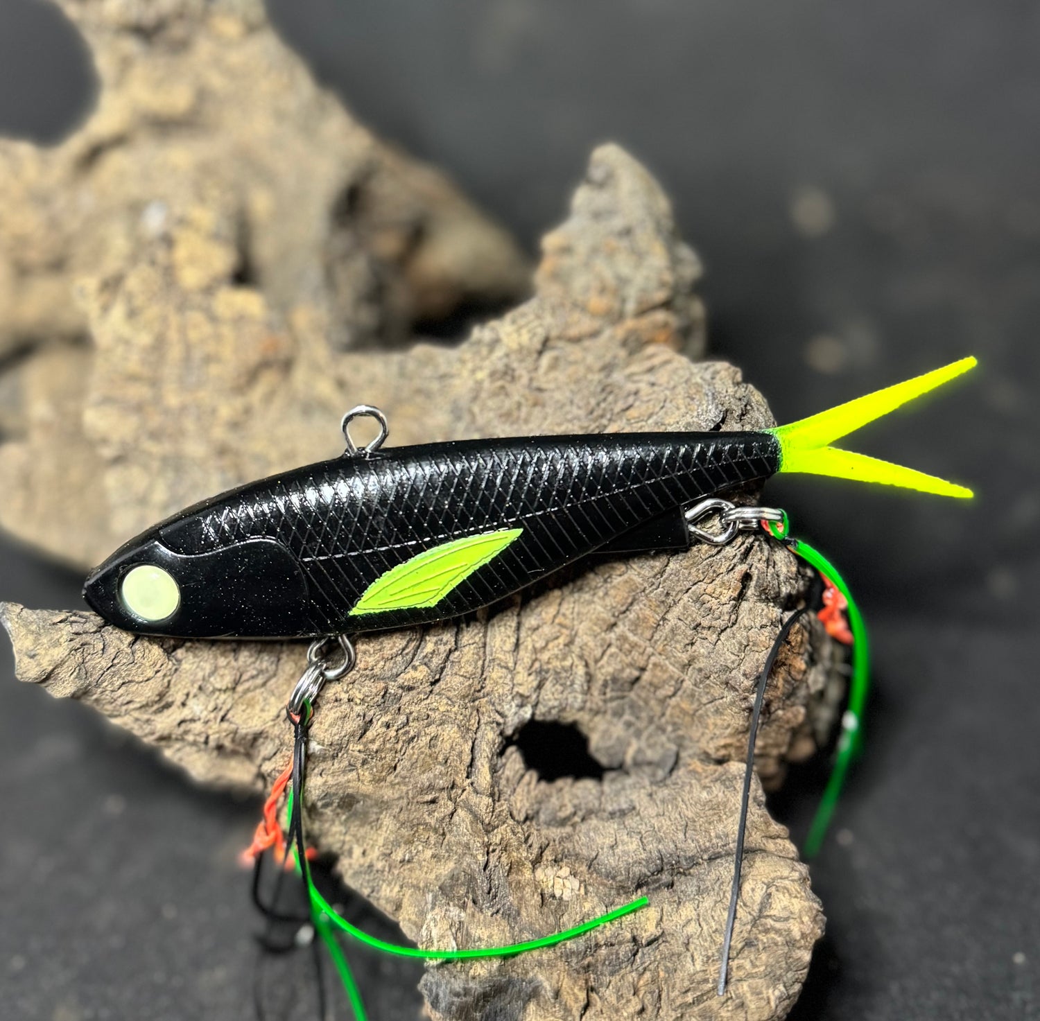 A multicoloured fishing lure with a vibrating tail designed to imitate the movement of fish, equipped with two sets of stinger hooks.