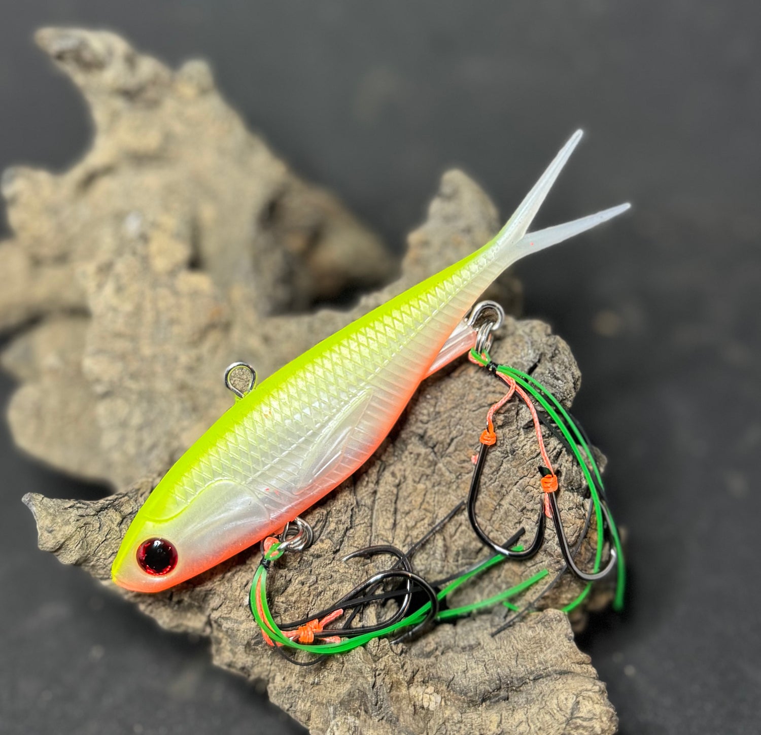 A multicoloured fishing lure with a vibrating tail designed to imitate the movement of fish, equipped with two sets of stinger hooks.