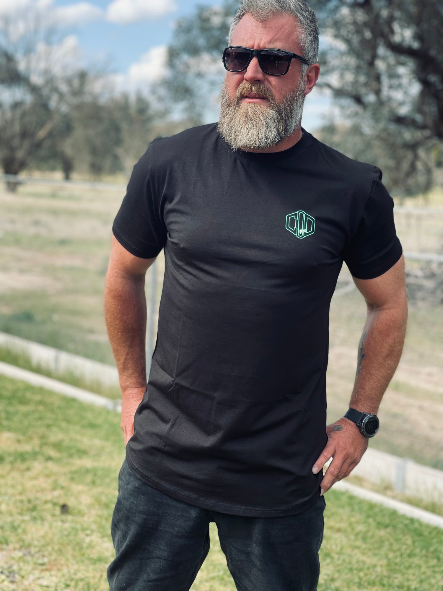 A man wearing a dad body t-shirt black short sleeve t-shirt with a subtle logo on the chest, 