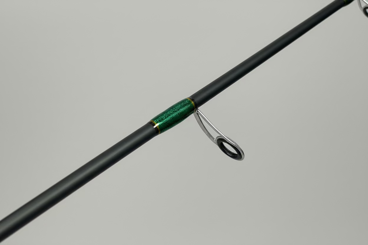 Close-up of a fishing rod handle with a green grip on a wooden floor.