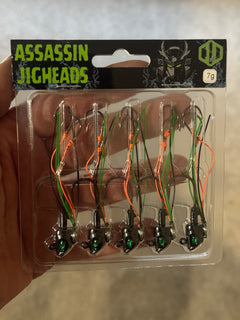A pack of 5 Assassin Jig heads fishing lures with green and orange colour scheme, displayed in a clear plastic packaging. yellow belly