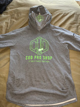 A grey hoodie with the text 'COD PRO SHOP' displayed prominently, featuring a hood and a built-in neck scarf. The hoodie is presented on a mannequin against a black background.