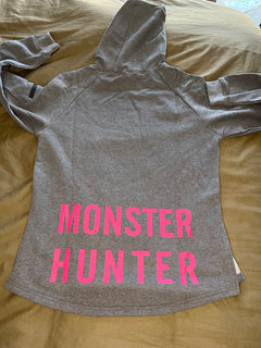 A grey hoodie with the text 'COD PRO SHOP' displayed prominently, featuring a hood and a built-in neck scarf. The hoodie is presented on a mannequin against a black background.